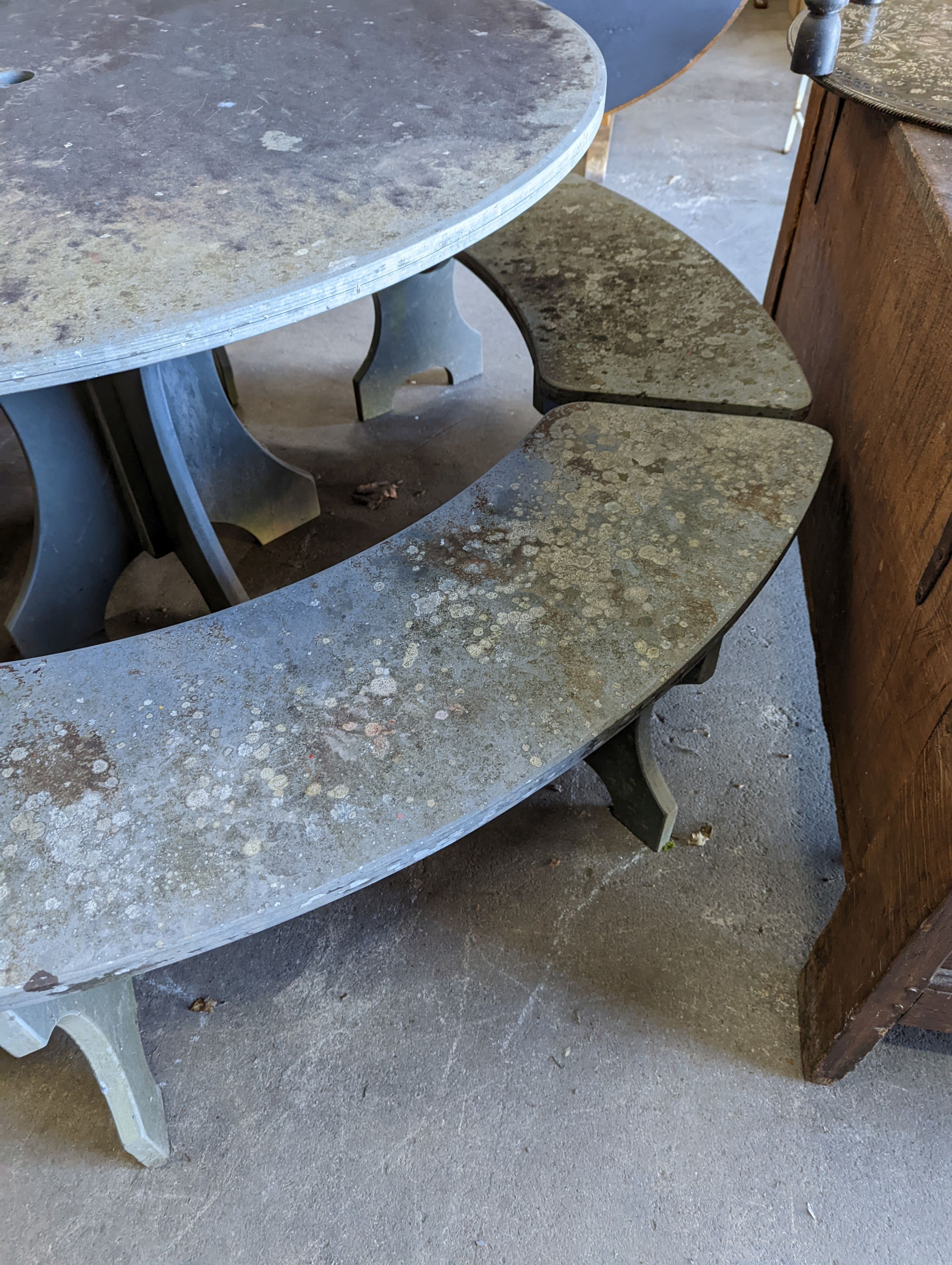 A heavy slate circular topped garden table, diameter 125cm, height 79cm together with four crescent shaped slate garden benches